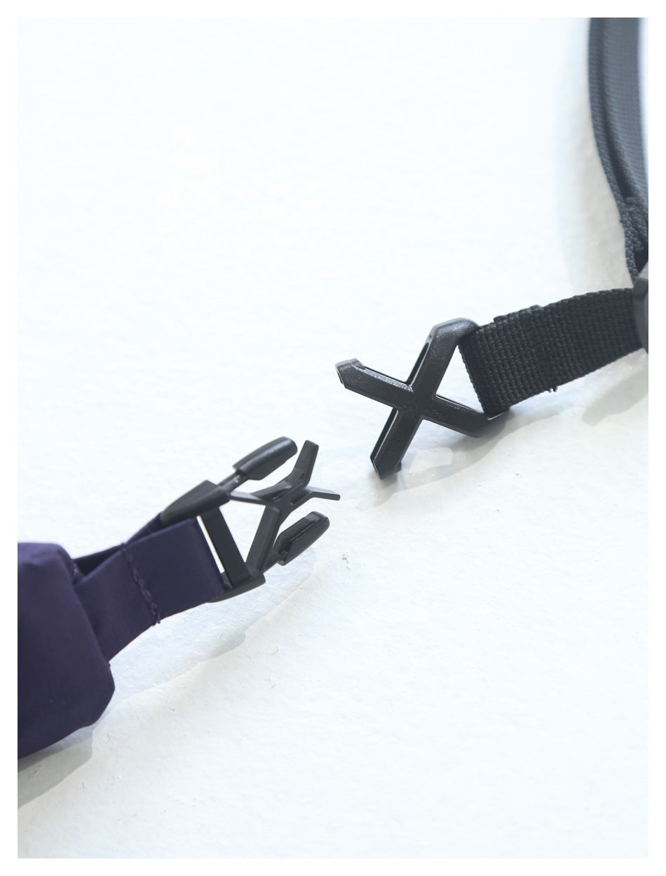 Close-up of black plastic X-shaped clips connecting a black strap to purple fabric.