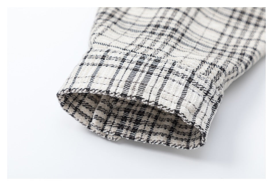 Close-up of a cream and black plaid shirt sleeve ending in a folded cuff.