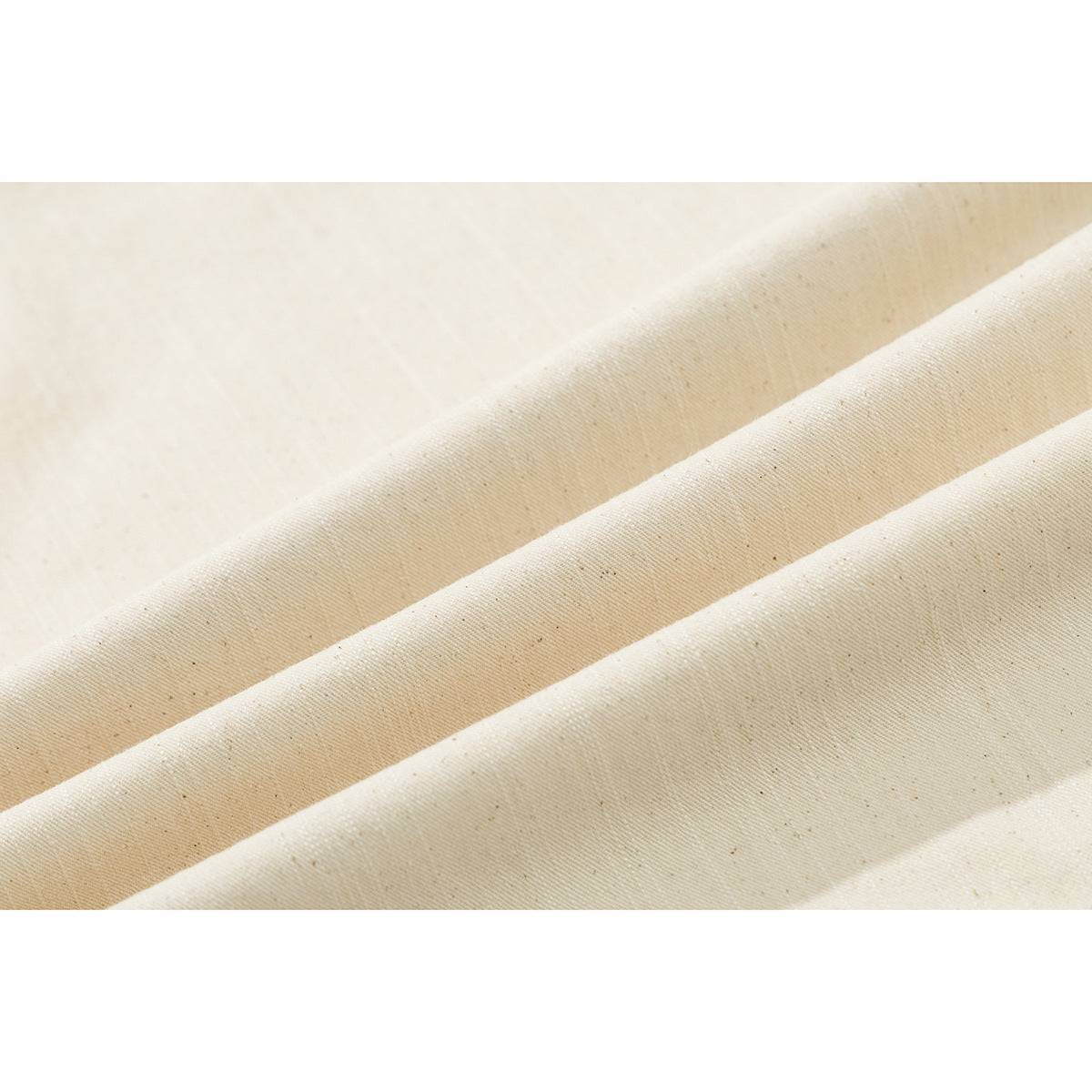 Macro view of ivory fabric arranged in soft diagonal folds, showing its fine woven texture.