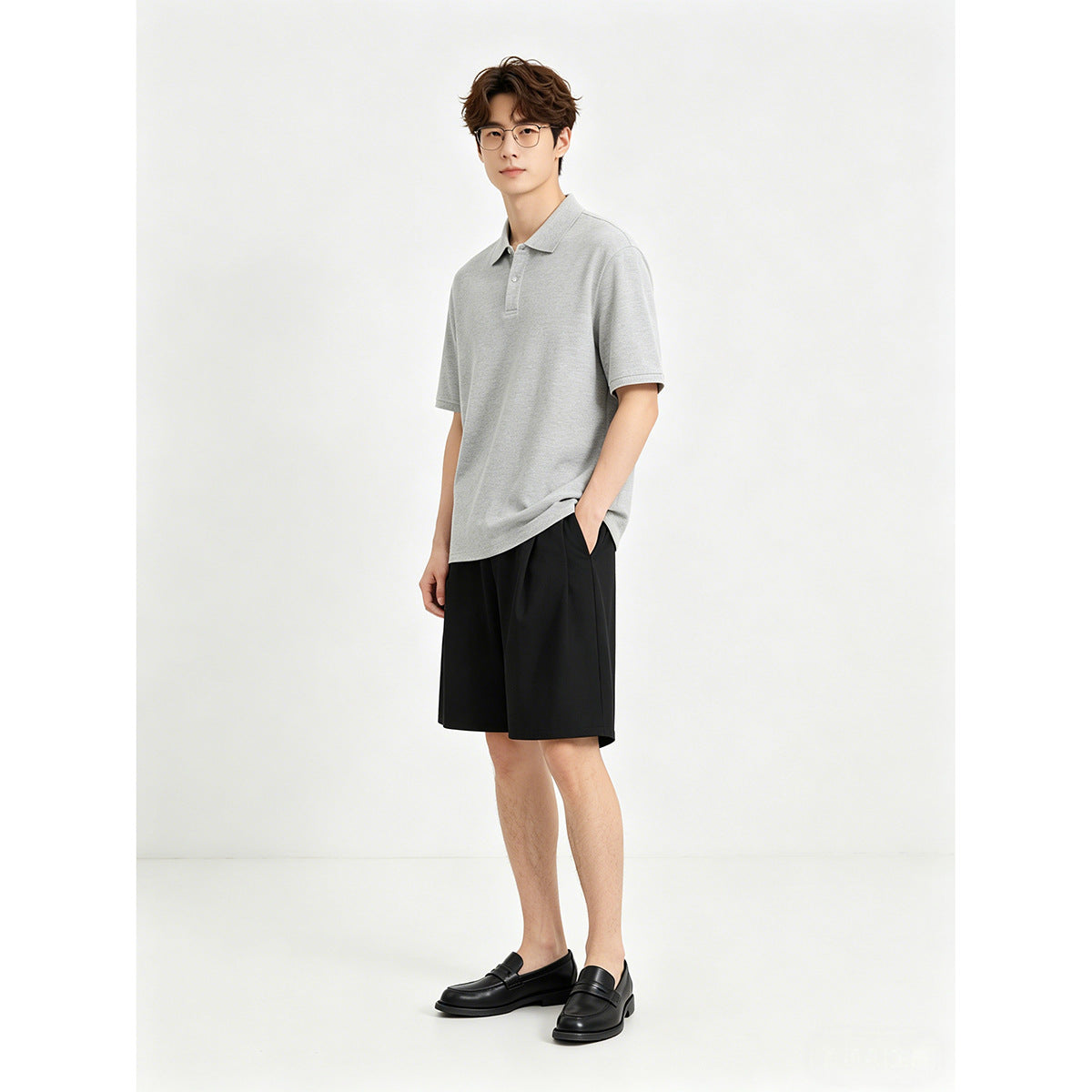 Model wearing a light gray short-sleeve polo shirt, black shorts and black loafers.
