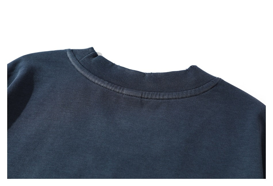 Close-up of a dark navy garment's ribbed crew neckline and stitched collar seam.