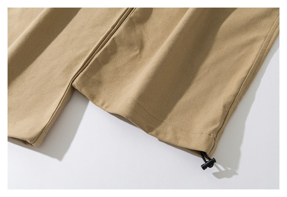 Close-up of tan pant hems with a black adjustment cord at one cuff.