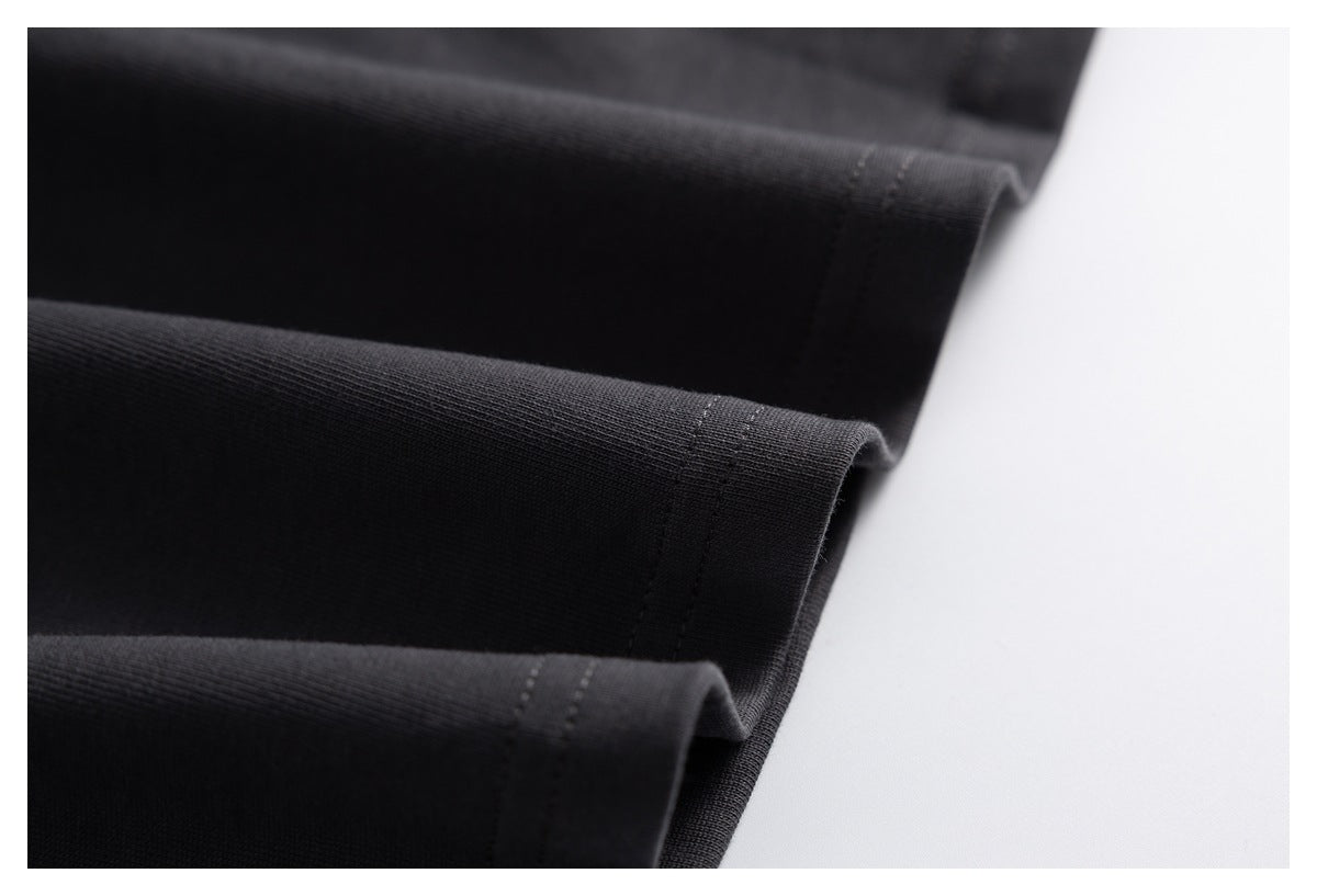 Close-up of black fabric folds with stitched hems against a white background.