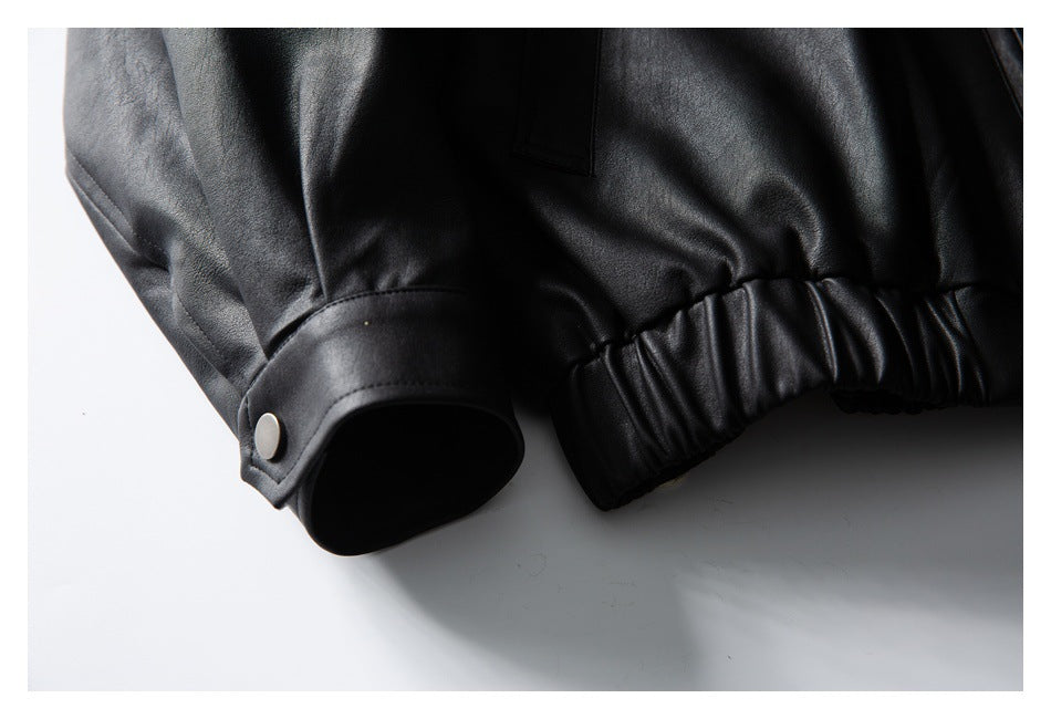 Close-up of a black jacket sleeve cuff with a silver snap and gathered elastic hem.