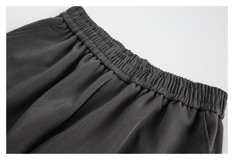 Close-up of the gathered elastic waistband and pleats on charcoal gray pants.
