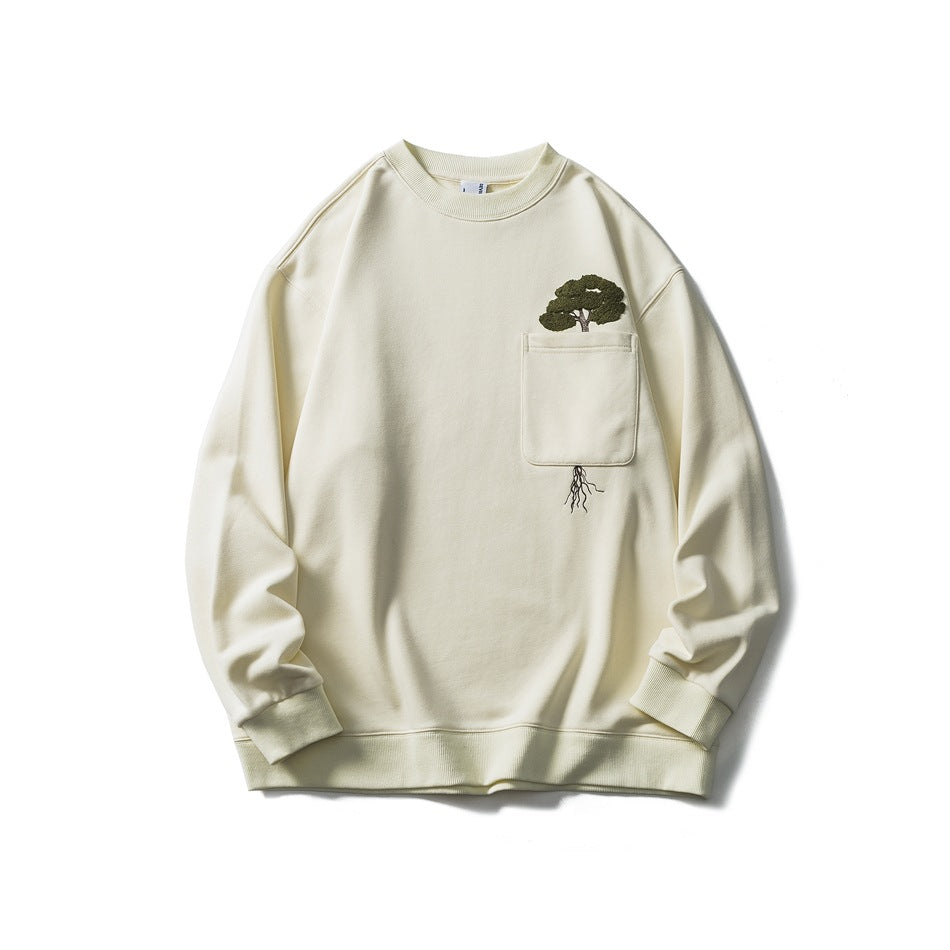 Beige crewneck sweatshirt flat lay with chest pocket and green embroidered tree with roots