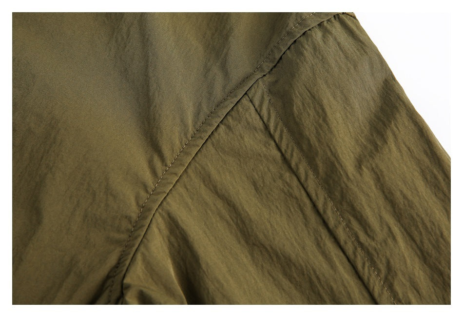 Close-up of olive-brown garment fabric with a curved stitched seam.