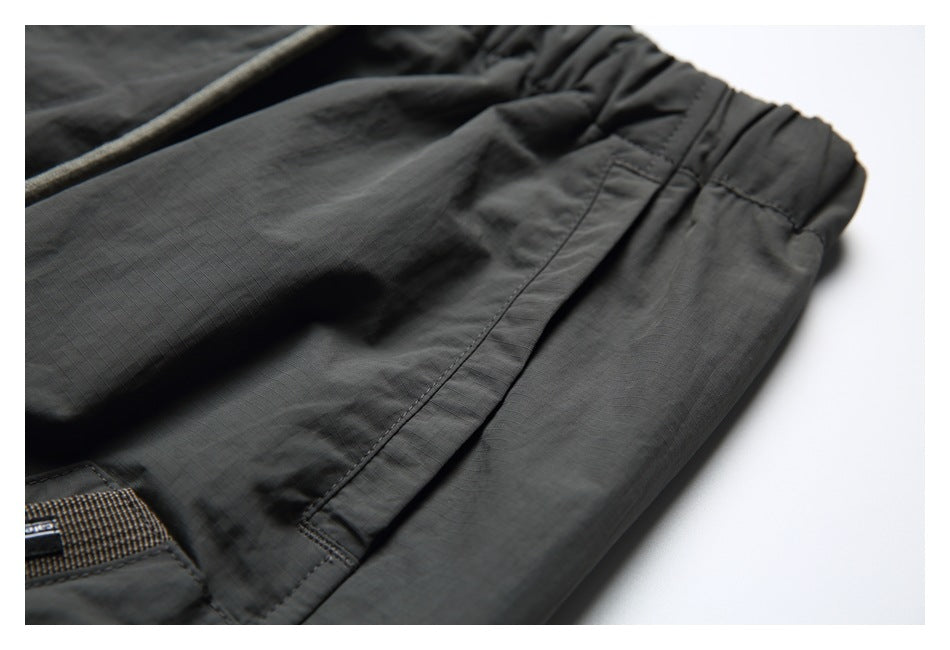 Close-up of charcoal pants showing the gathered elastic waistband and a side pocket.