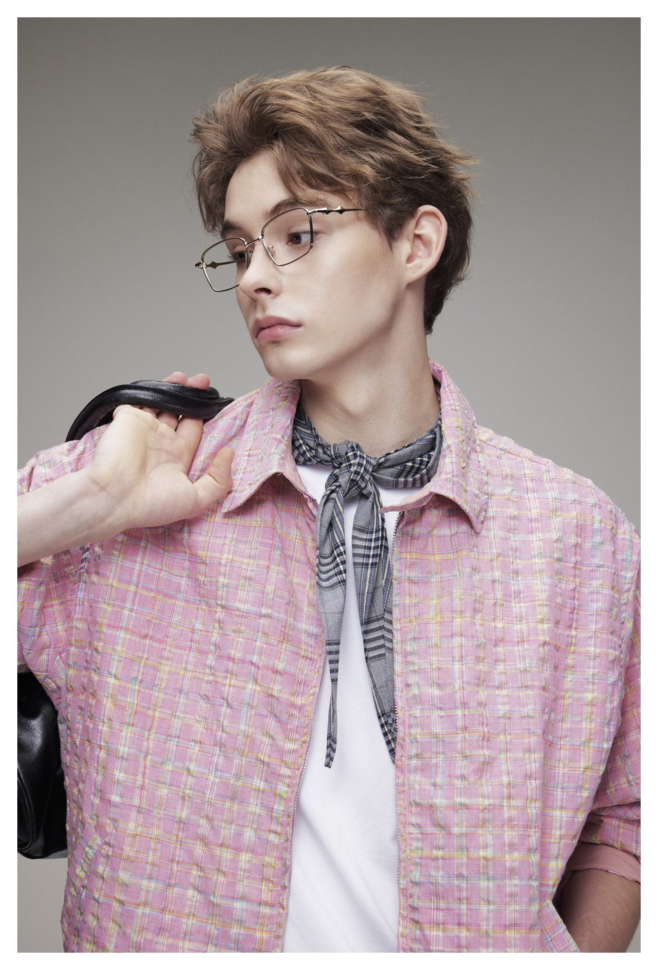 Close front view of a model in a pink plaid jacket over a white shirt, with a gray plaid scarf at the neck.