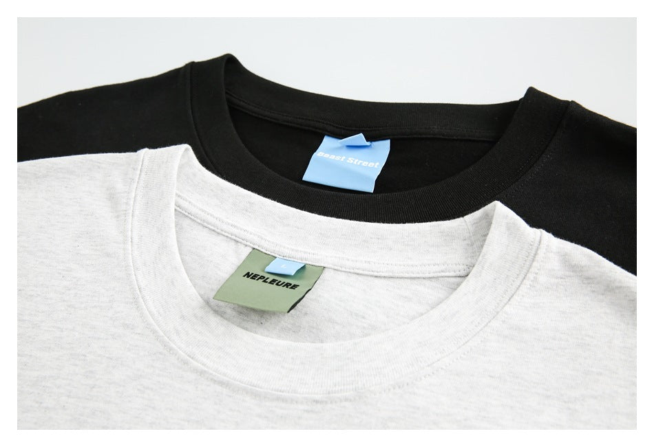 Close-up of overlapping light gray and black T-shirt collars with visible neck labels.