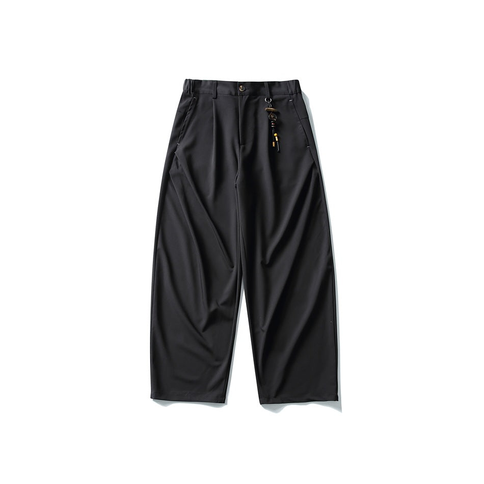 Black wide-leg pleated trousers flat lay with front button and beaded charm on belt loop