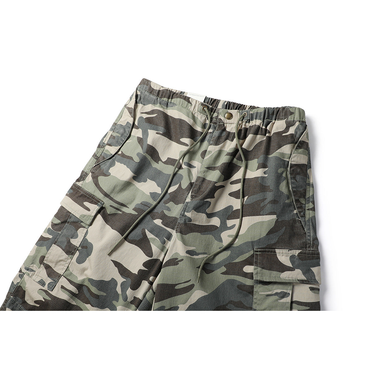 Close front view of loose camouflage cargo pants with an elastic waist, drawcords and flap pockets.