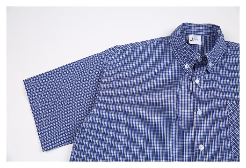 Cropped flat lay of a blue checked short-sleeve shirt, showing its button-down collar and chest pocket.