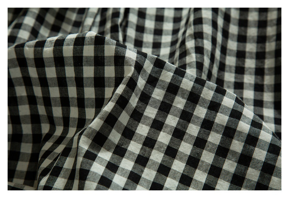 Close-up of draped black-and-white gingham fabric showing its check pattern.