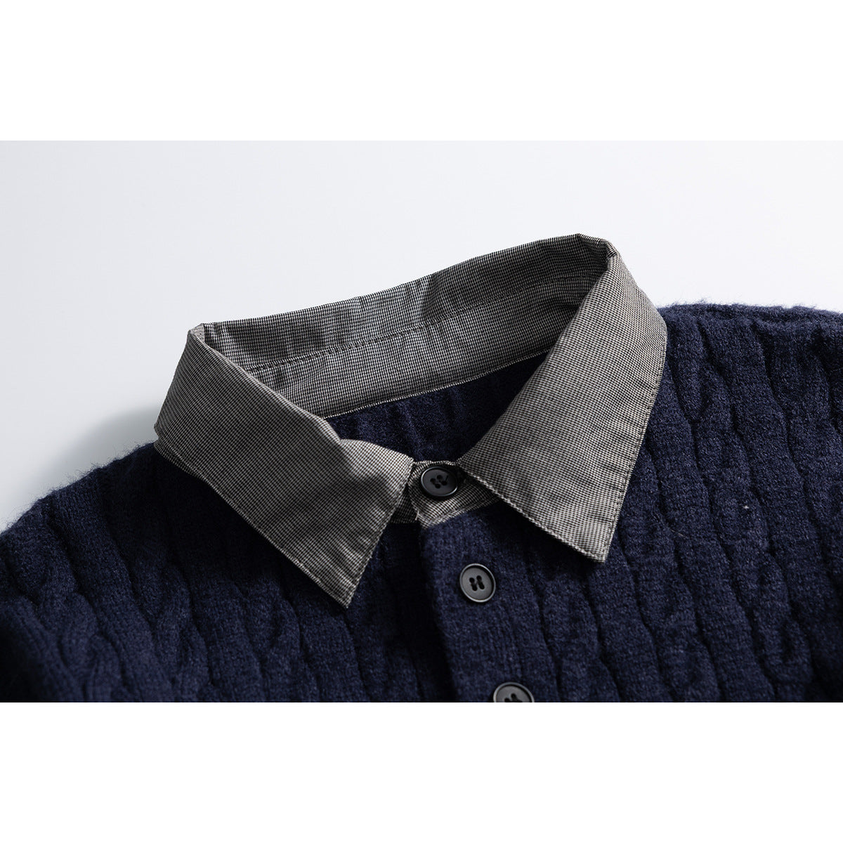 Close-up of a navy cable-knit sweater with a gray microcheck collar and dark buttons.