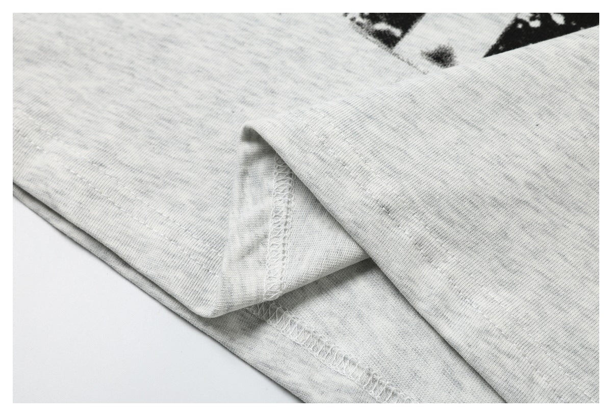 Close-up of the light gray T-shirt's folded hem and overlock stitching.