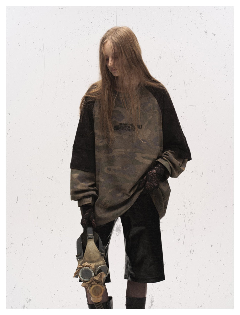 Model wearing an oversized brown camouflage raglan shirt with black sleeves and black shorts, shown at an angle.