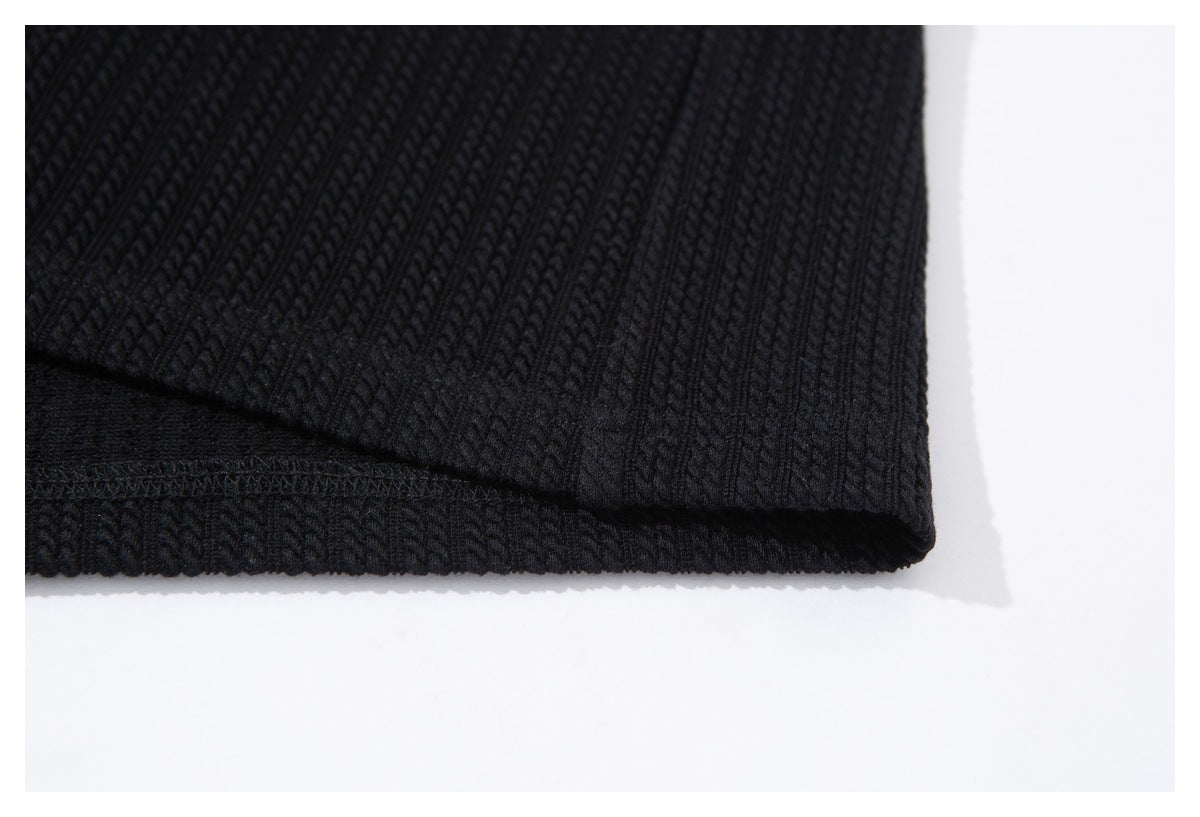 Close-up of the stitched hem and textured knit on a black garment.