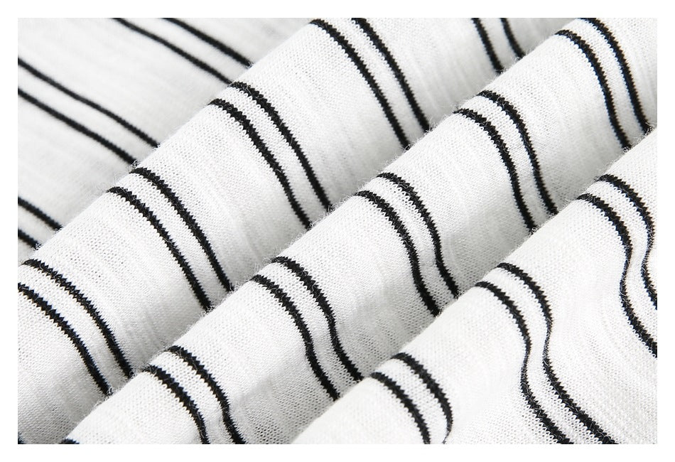 Close-up of white knit fabric with thin black stripes, folded to show its texture.