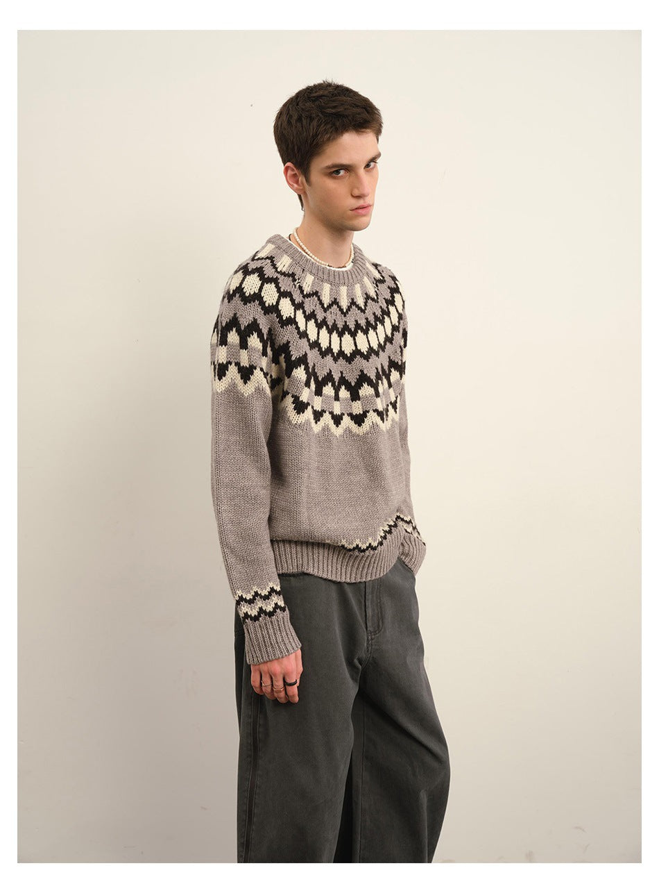 Three-quarter view of a model wearing a taupe gray sweater with a black and cream geometric yoke.