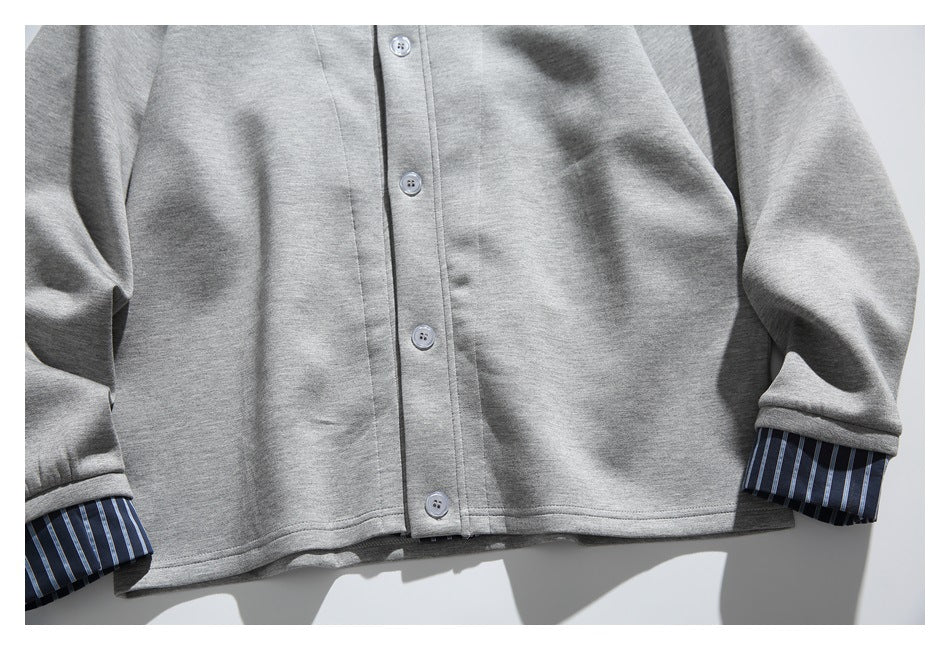Lower front of a gray button-front jacket, with blue striped fabric visible at the sleeve cuffs.
