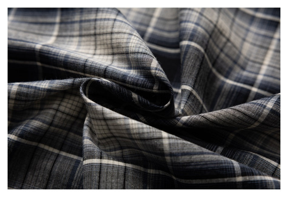 Close-up of black, gray, and beige plaid fabric gathered into folds, showing its checked pattern.