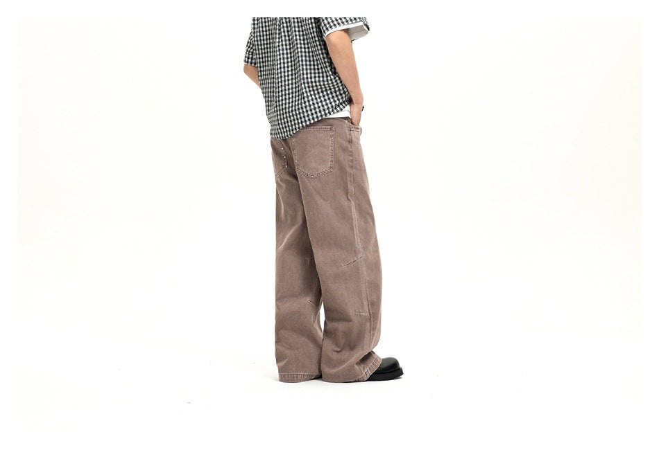 Side-rear view of a model wearing loose taupe jeans with a rear patch pocket and wide legs.
