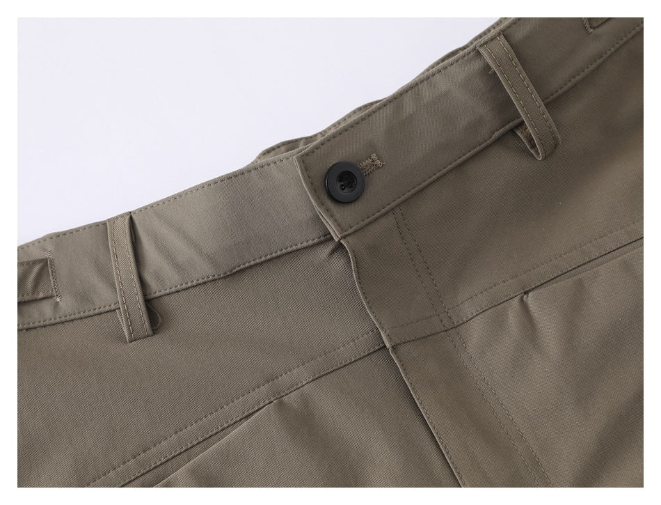 Close-up of the taupe shorts' waistband, belt loops, button closure, and pocket seam.