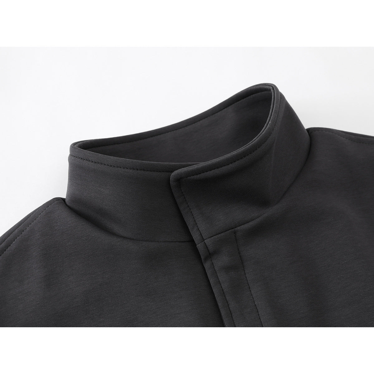 Close-up of a charcoal jacket's raised stand collar and overlapping front placket.