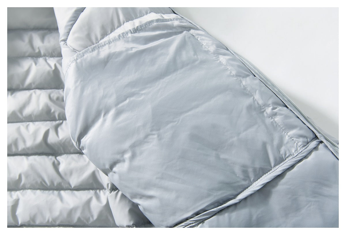 Close-up of a light gray quilted puffer jacket showing padded panels, stitching, and a folded edge.
