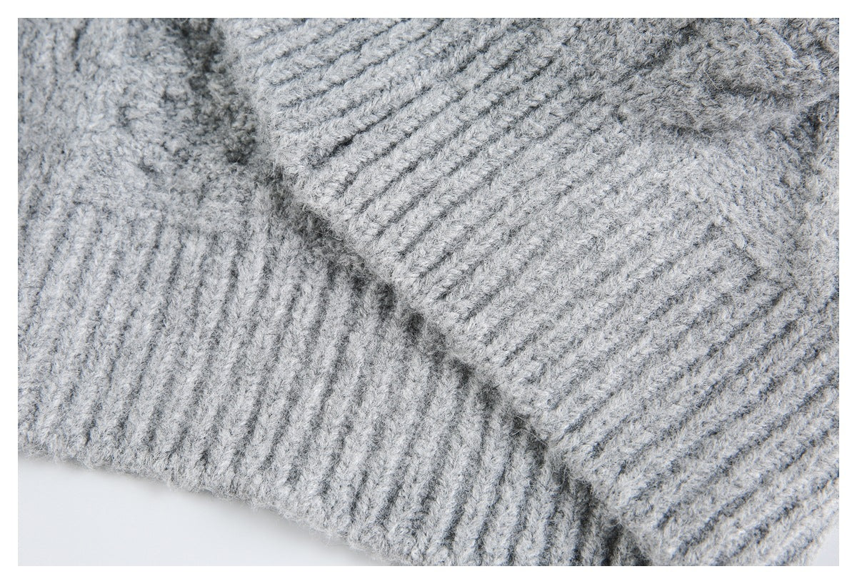 Close-up of a light gray sweater showing a ribbed edge meeting textured knit fabric.