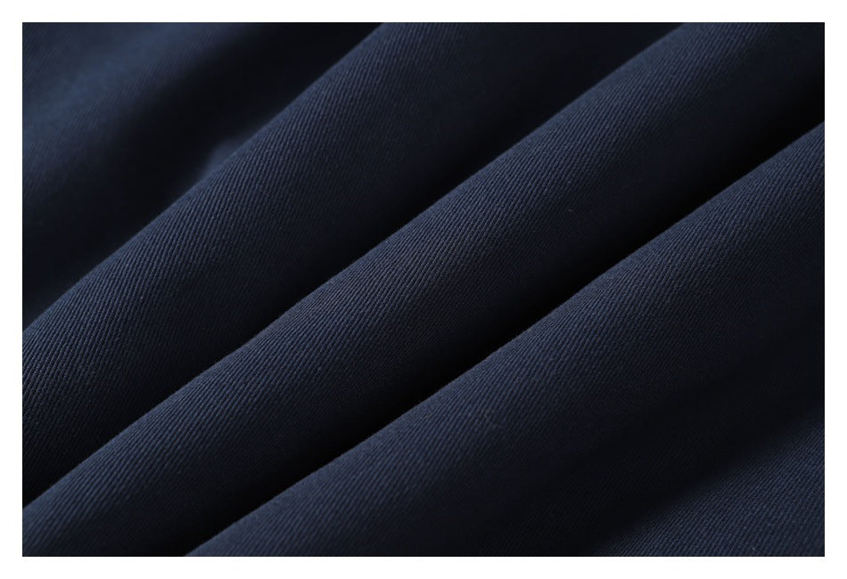 Close-up of dark navy fabric folded into soft ridges, showing a fine diagonal weave.