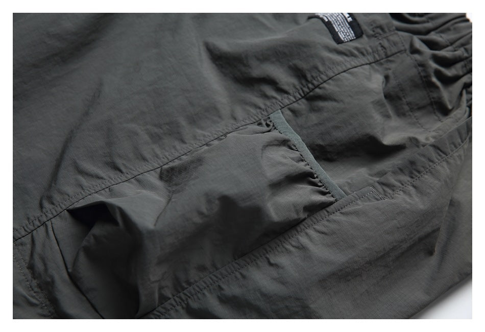 Close-up of a dark charcoal garment showing a stitched pocket and panel seams.