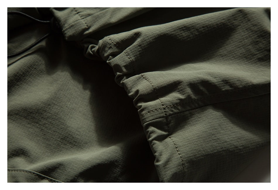Close-up of olive-green fabric with a gathered, stitched section and overlapping folds.