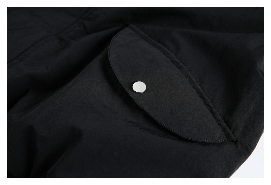 Close-up of a black garment flap with a round silver snap fastener.