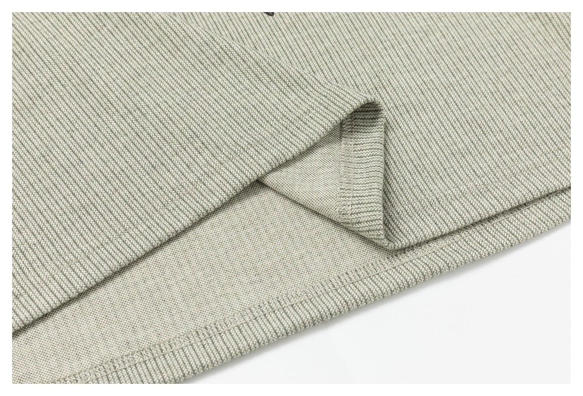 Close-up of a stitched hem and reverse side of gray and off-white textured fabric.