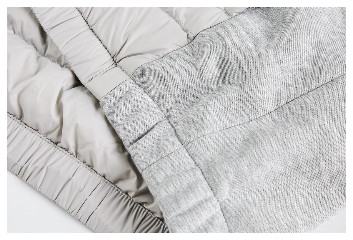 Close-up showing the heather-gray knit panel beside the light gray jacket's quilted section and gathered edge.