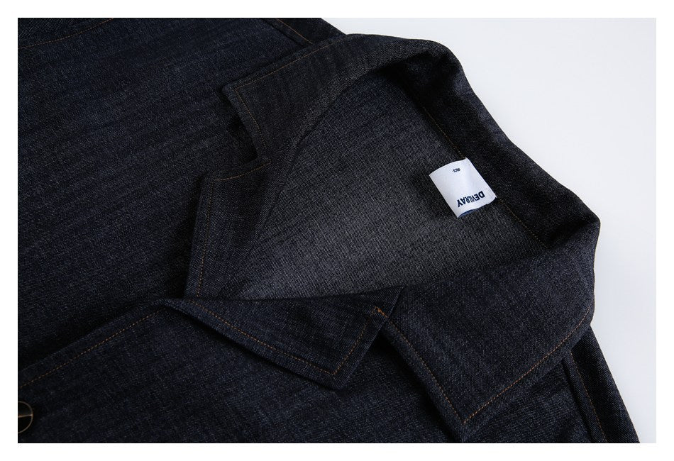 Dark indigo denim shown inside out, with orange stitching and a small white sewn-in label.