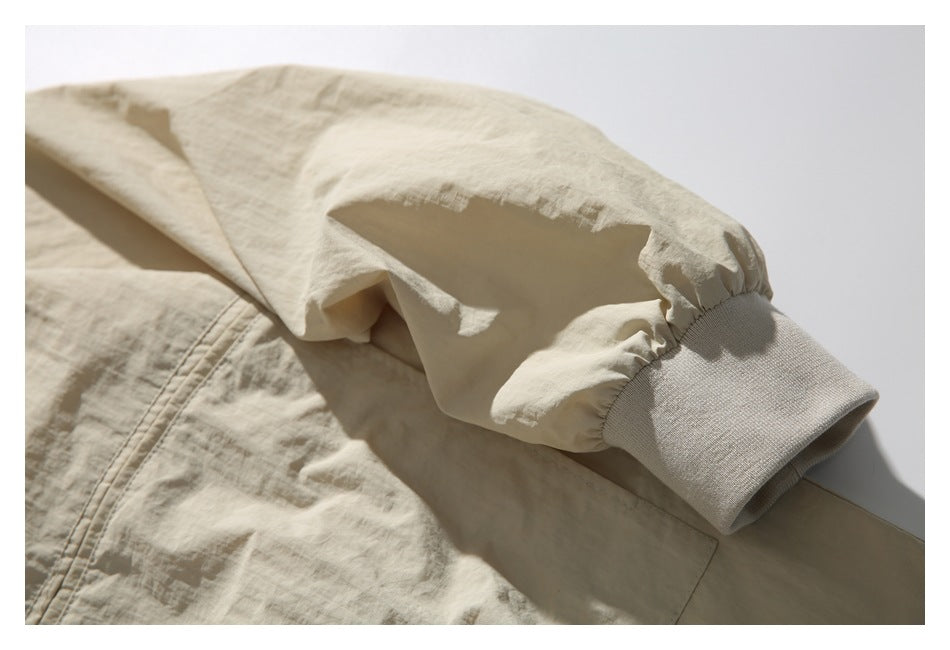 Close-up of a gathered beige jacket sleeve ending in a wide ribbed cuff.