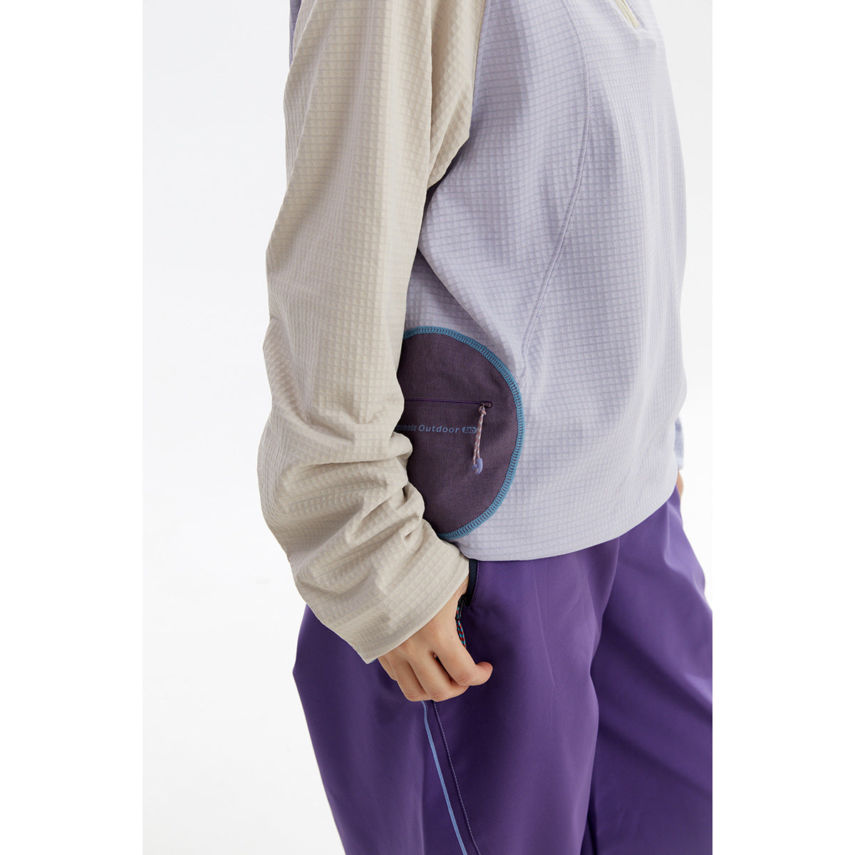 Close-up of the top’s textured fabric, contrasting sleeves, curved teal-trimmed pocket, and purple pants.
