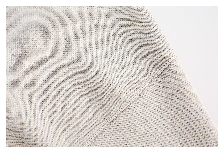Close-up of a light beige knit garment showing a diagonal seam and fine open-knit texture.