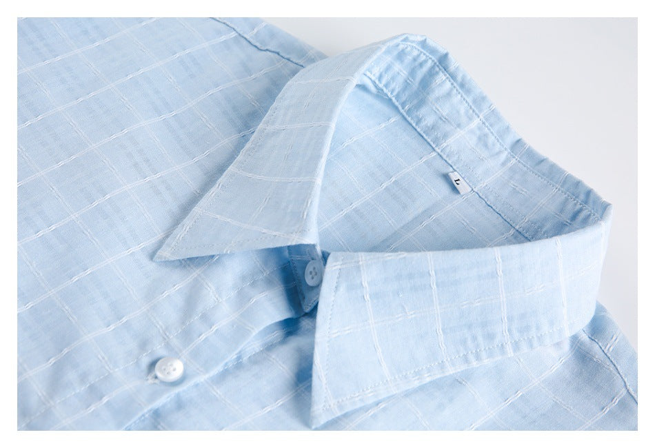Close-up of a light blue checked shirt collar, placket and white buttons.