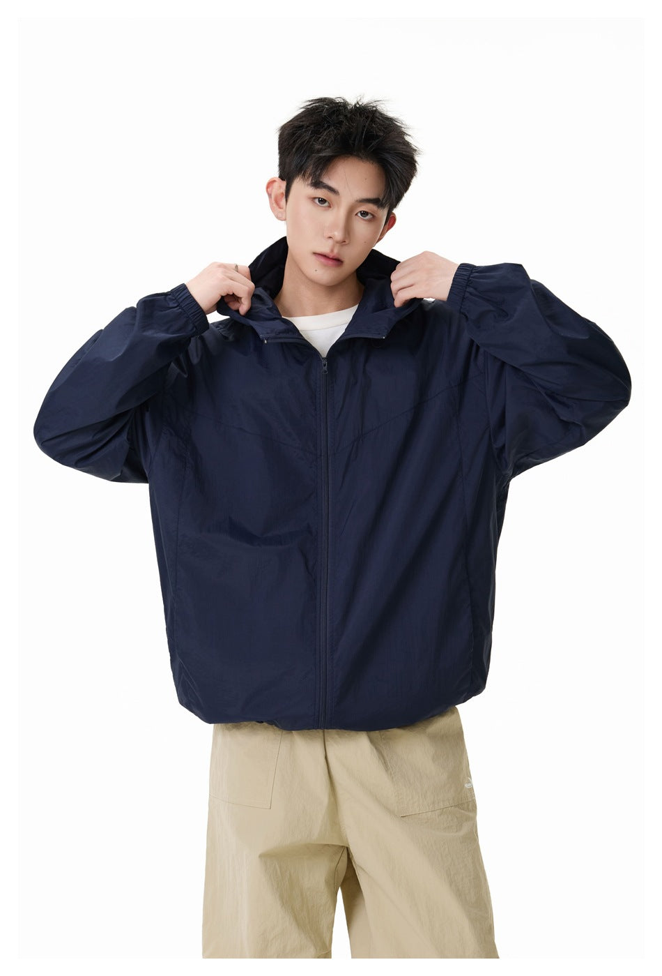 Model wearing a navy hooded zip jacket over a white shirt, shown from the front.