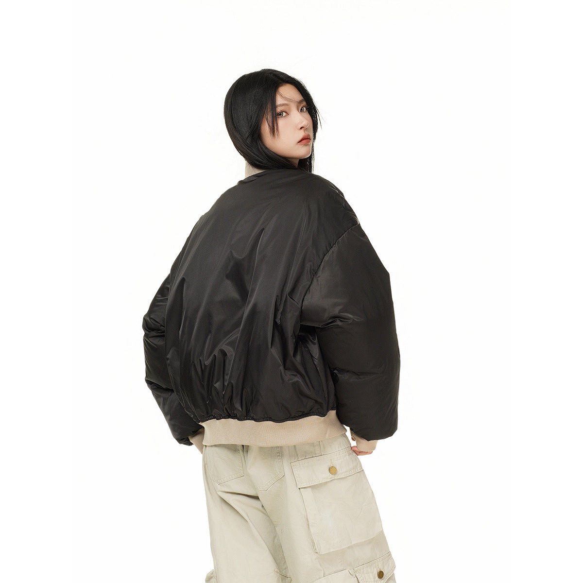 Model turned away, showing the back of an oversized black bomber jacket with voluminous sleeves.