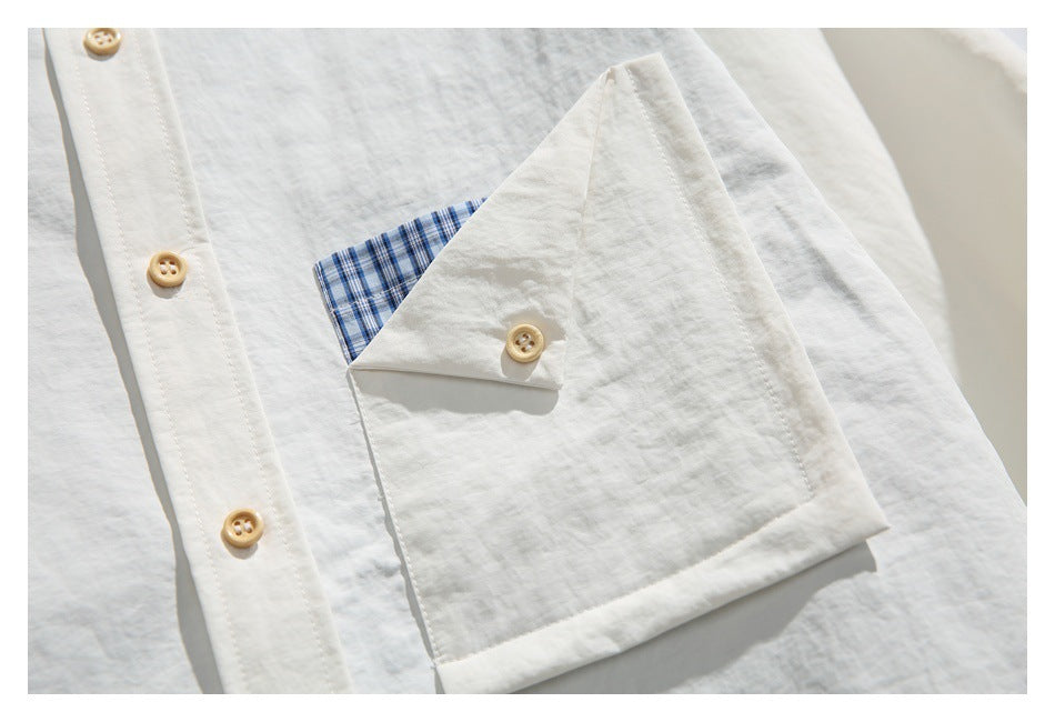 Close-up of the off-white shirt pocket flap, tan buttons, and blue checked pocket lining.