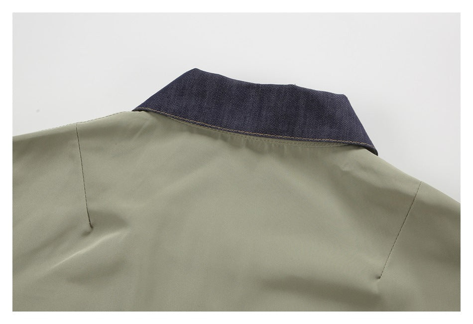 Close-up of an olive-gray garment's back shoulder and dark indigo collar with contrast stitching.