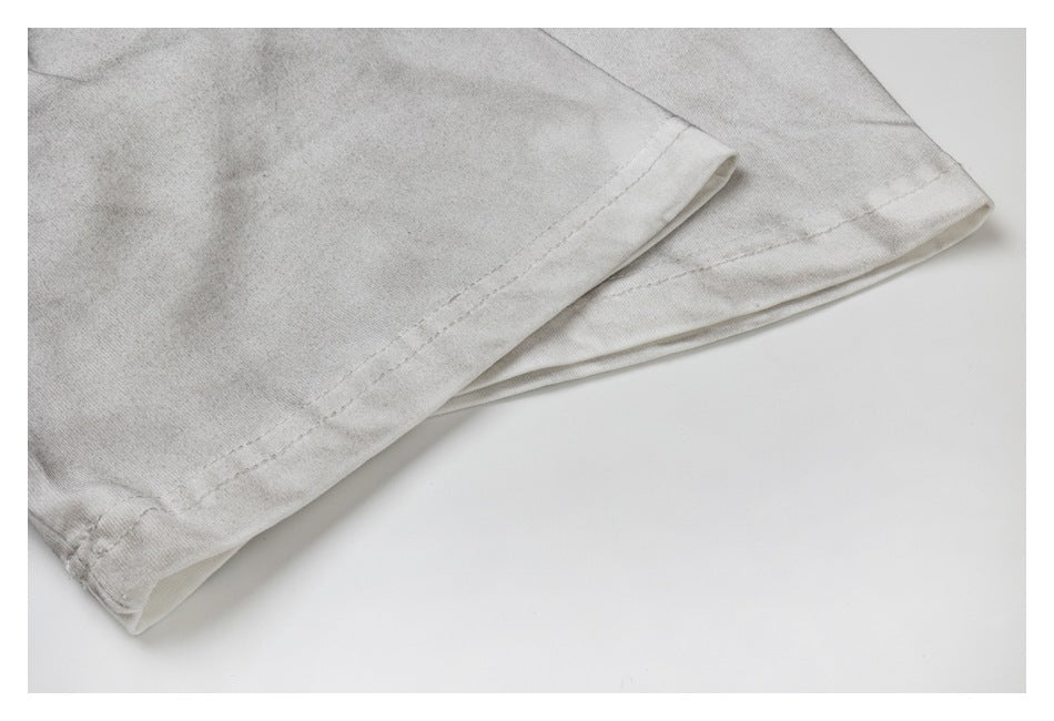 Close-up of a light gray garment edge with stitched hem and folded fabric.