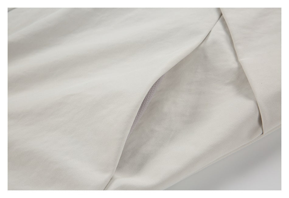 Close-up of pale beige garment fabric with a curved seam and overlapping panel.