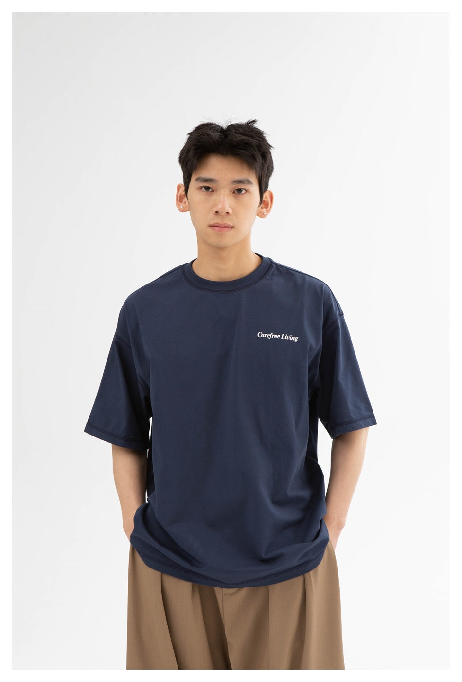 Closer front view of a model wearing a navy crew-neck T-shirt with a small white chest print.