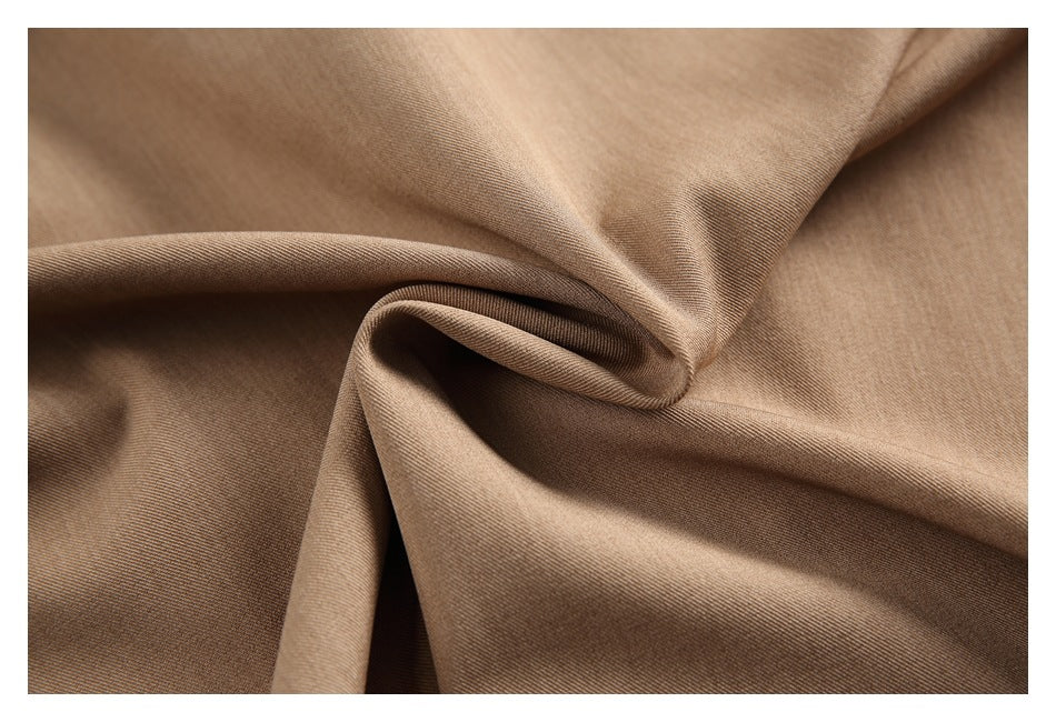 Close-up of tan fabric gathered into folds, showing its fine surface texture.